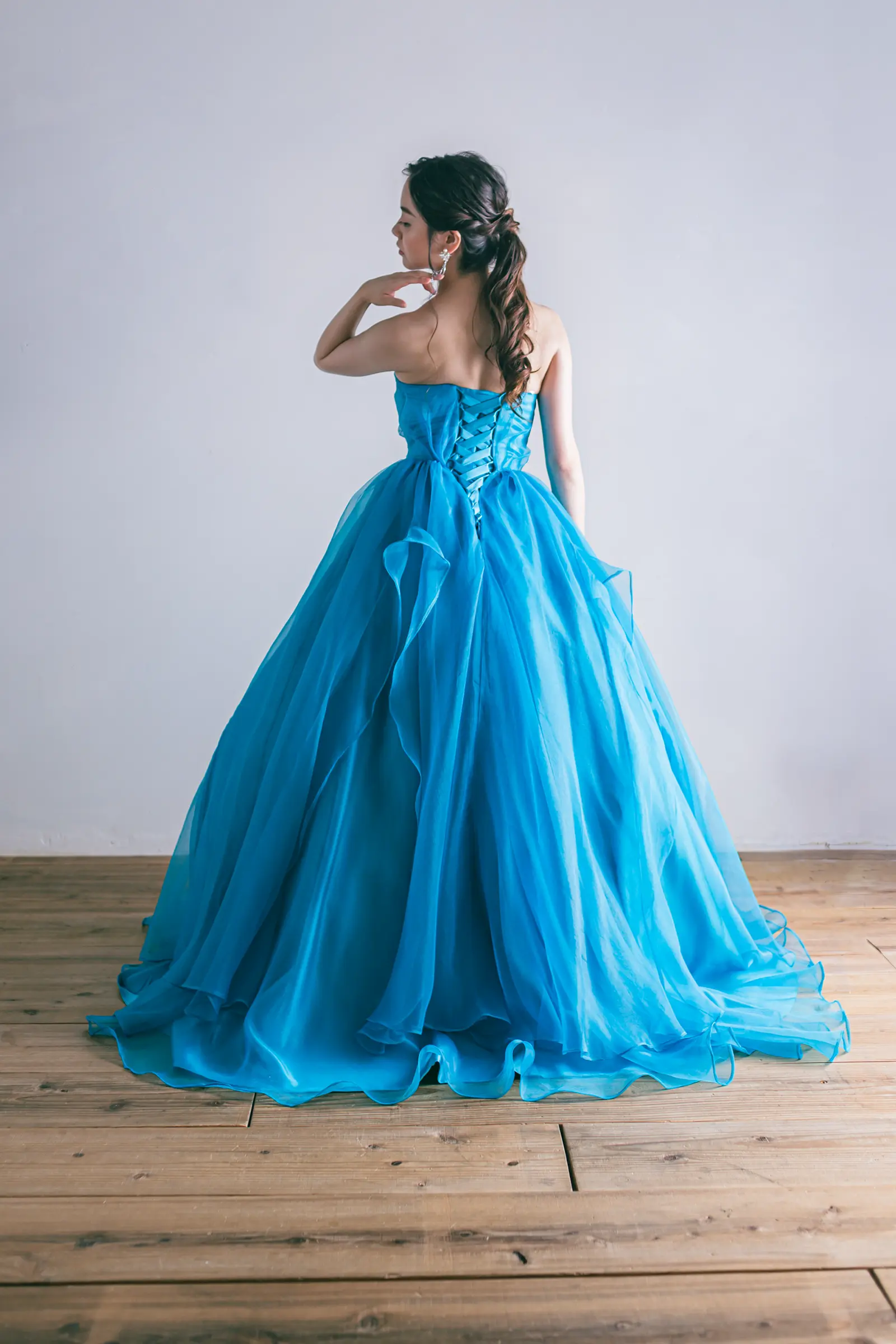 背中の編み上げデザインとボリューム感のあるチュールスカートが美しい、ターコイズブルーのドレスの後ろ姿。フォトウェディングや前撮りのバックショットに。