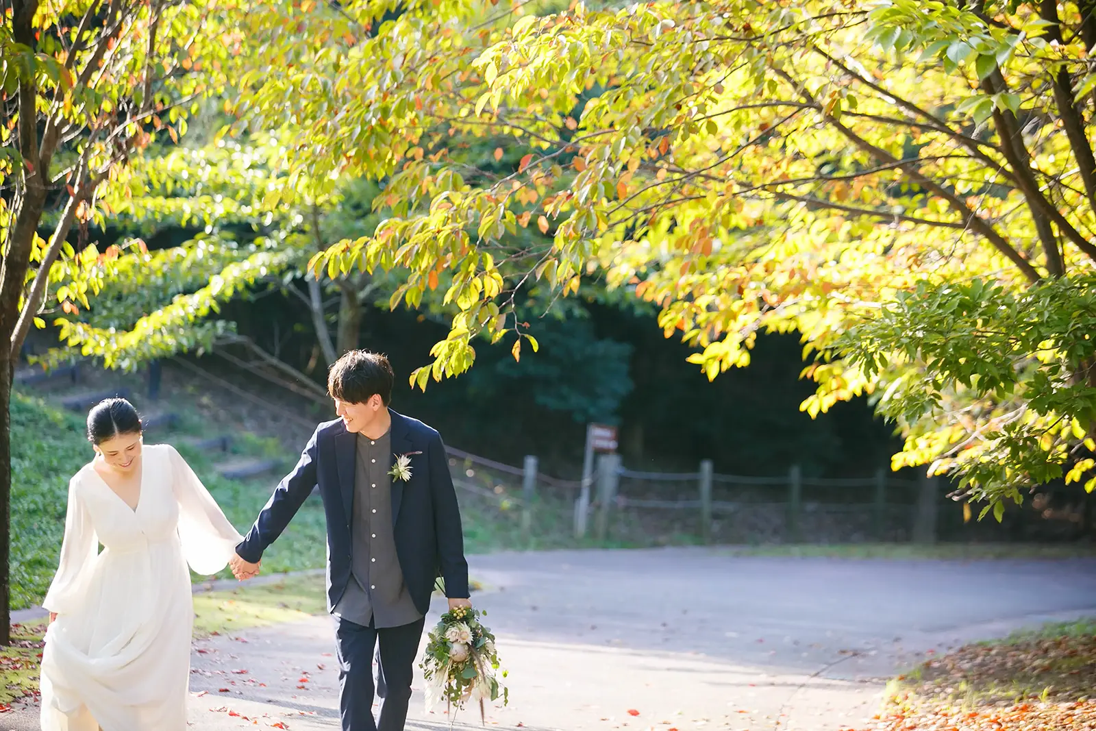 大乗寺丘陵公園の並木道で手をつないで歩く新郎新婦のフォトウェディング