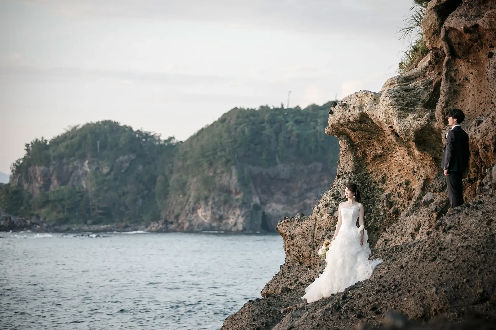 石川県の巌門で海と岩場を背景に撮影する新郎新婦のフォトウェディング