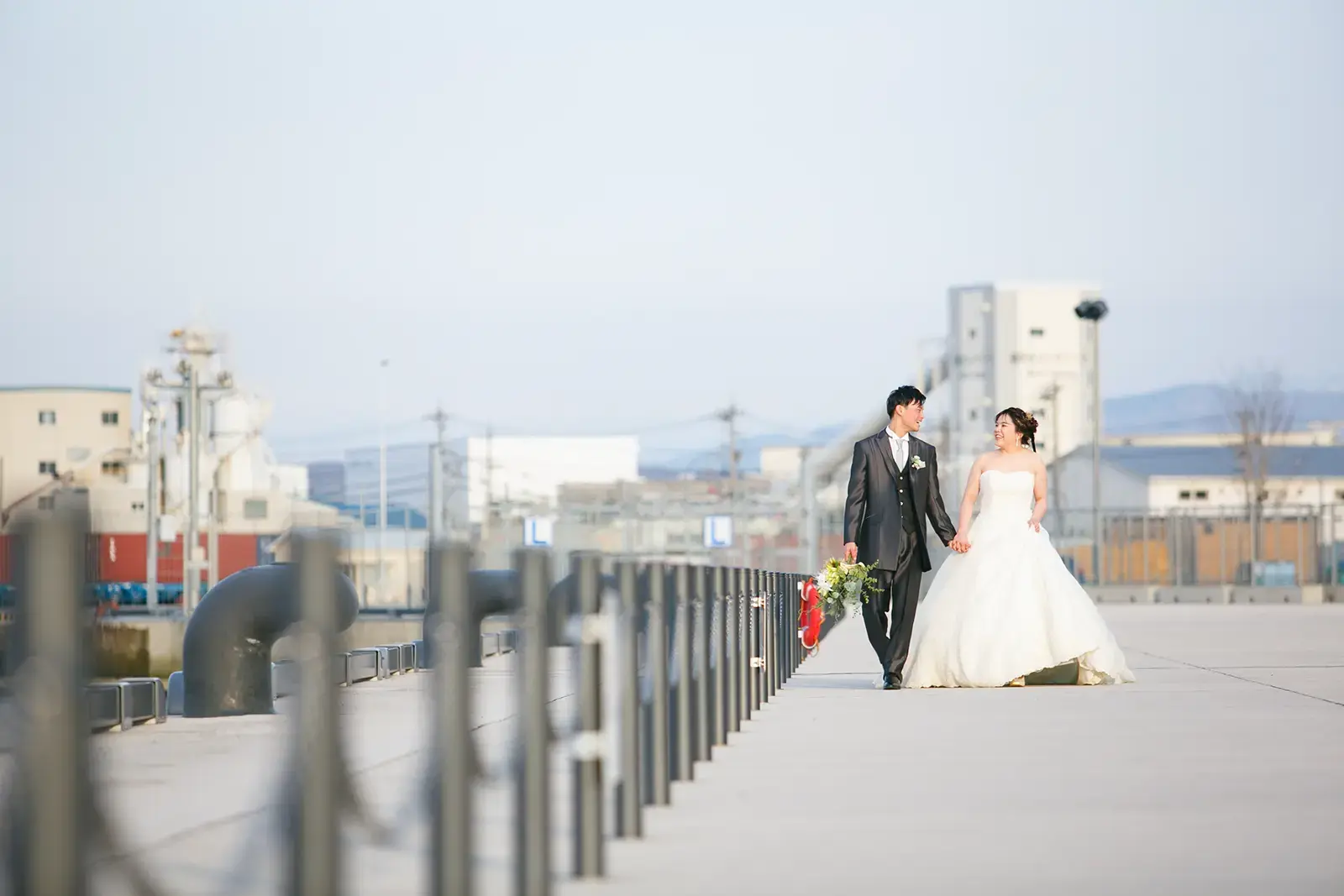 金沢港クルーズターミナルでドレス姿の新郎新婦が海辺を歩くフォトウェディング