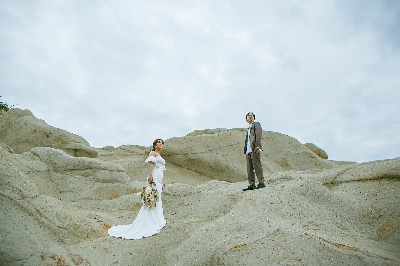 片野海岸の岩場でドレス姿の新婦と新郎が撮影する絶景フォトウェディング