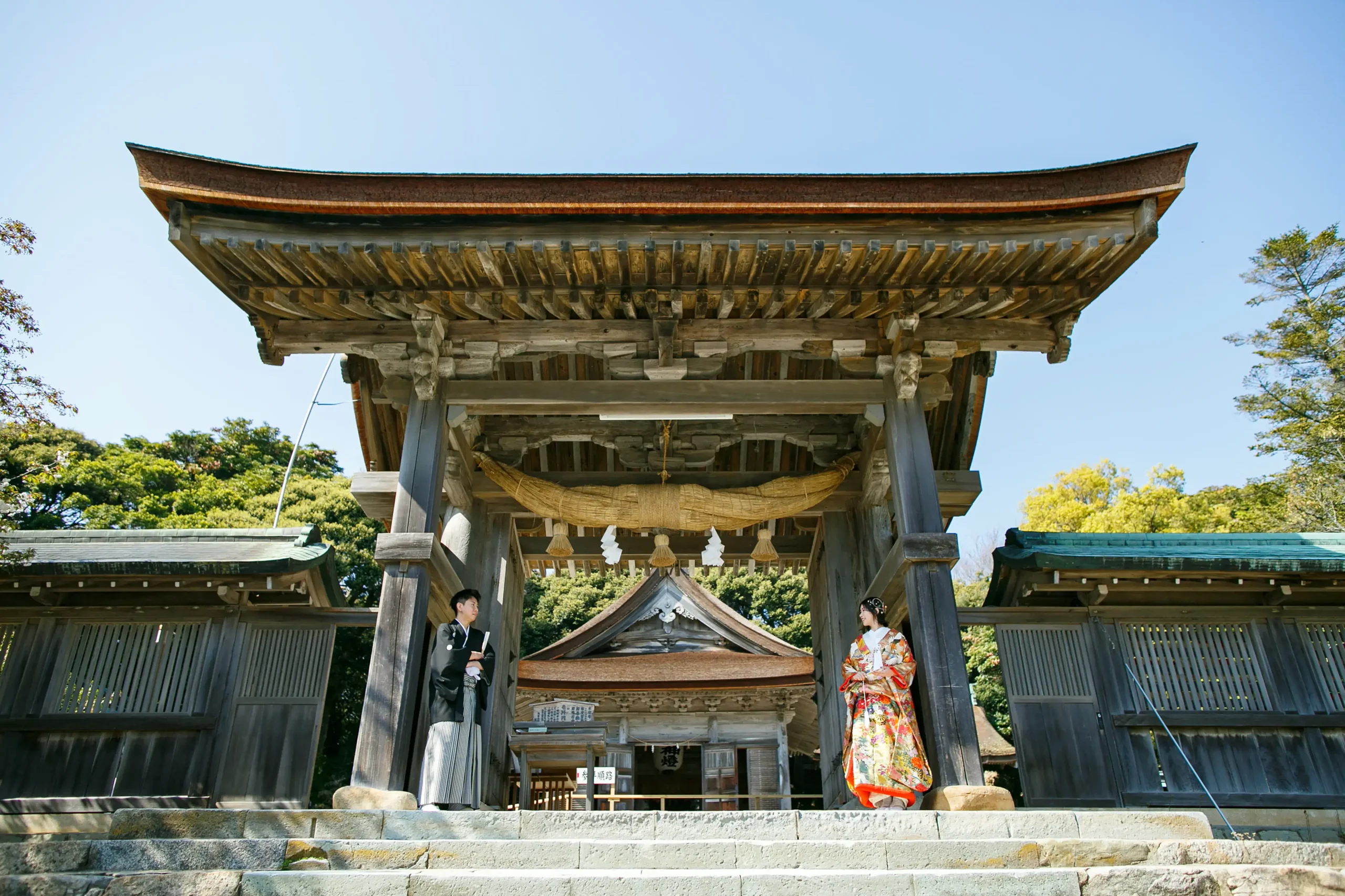 気多大社の大鳥居前で色打掛と紋付袴を着て撮影する新郎新婦