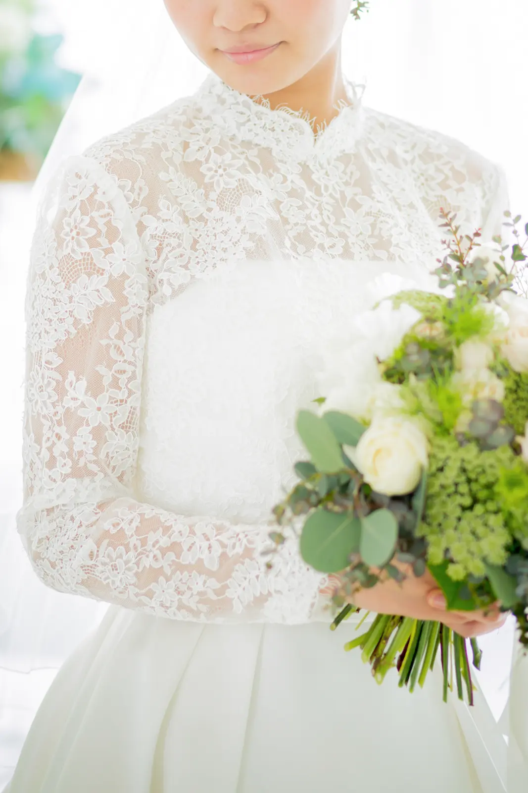 繊細な総レースの長袖ウェディングドレスを着用し、ナチュラルなブーケを持つ花嫁。フォトジェリッシュが提案するクラシカルで上品なドレススタイル。