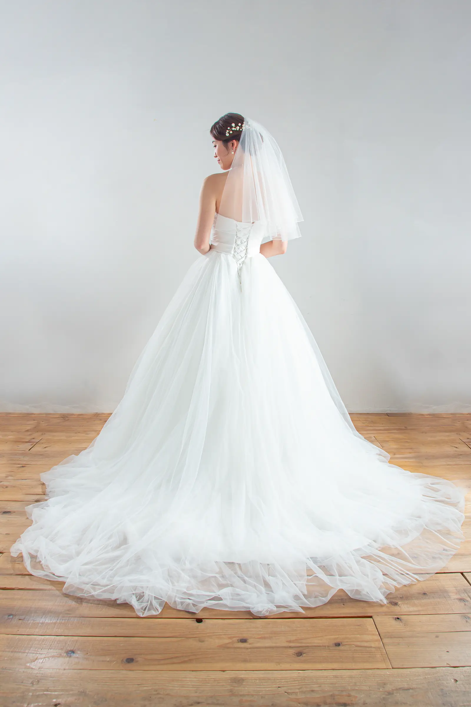 繊細なレースをあしらったショートベールの全身後ろ姿。ウェディングドレスのバックスタイルを引き立てる一枚。