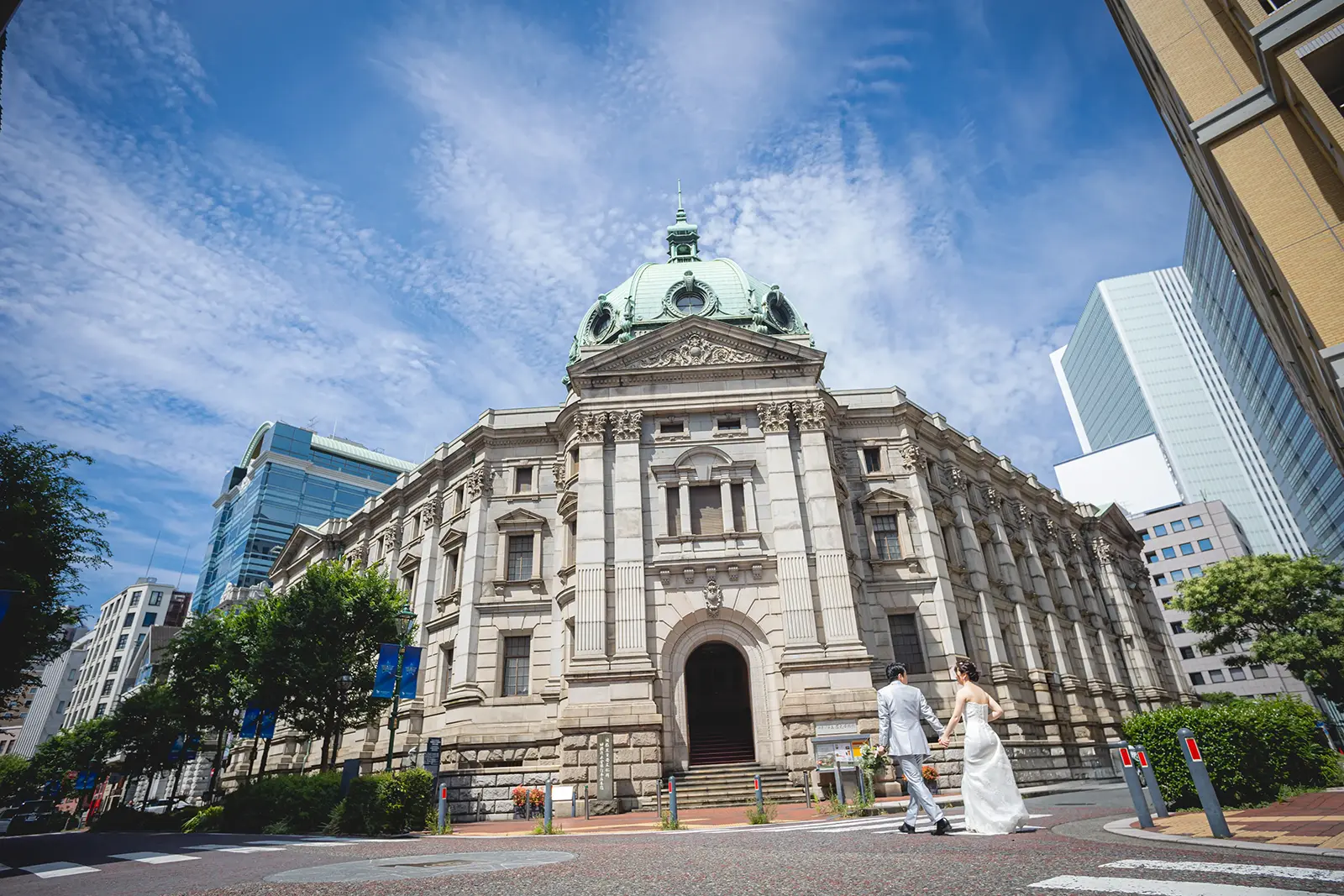 馬車道にある神奈川県立歴史博物館の重厚な建築を背景に、ウェディングドレスとタキシード姿で微笑むカップル。フォトジェリッシュによる、横浜らしい洗練された前撮り。